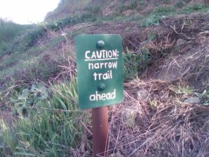Sign reads "Caution: narrow trail ahead"