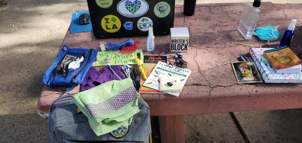 Picnic table covered in items including laptop, books, pens